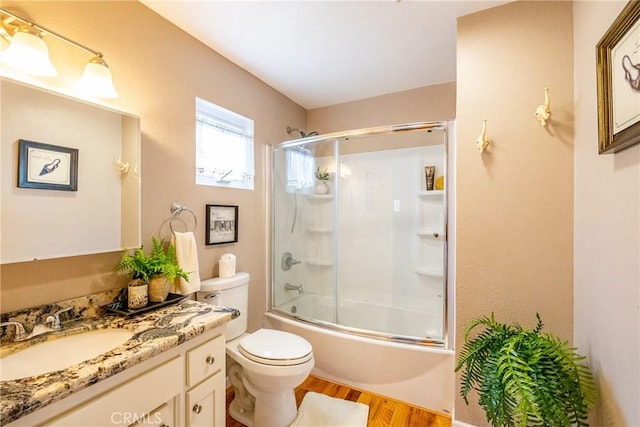 full bathroom with toilet, vanity, bath / shower combo with glass door, and hardwood / wood-style flooring