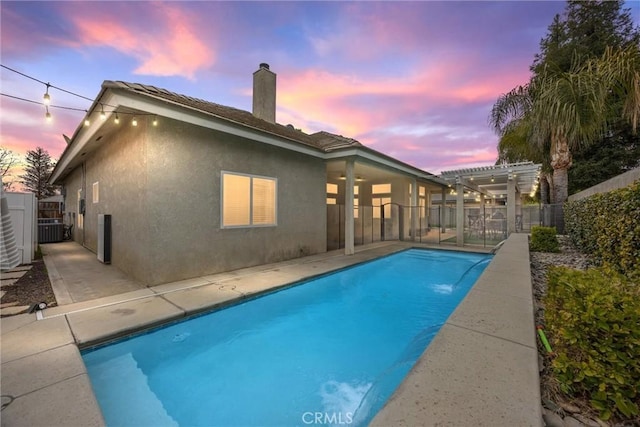 pool at dusk with a patio, a pergola, and pool water feature