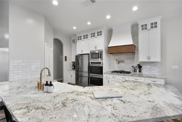 kitchen with white cabinetry, premium range hood, sink, and stainless steel appliances