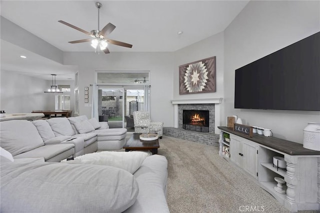 carpeted living room with ceiling fan and a brick fireplace