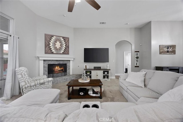 carpeted living room with ceiling fan and a fireplace