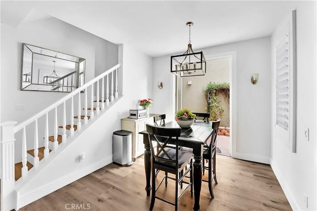 dining area with light hardwood / wood-style floors and an inviting chandelier