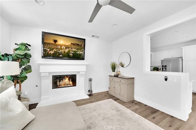 living room with ceiling fan and light hardwood / wood-style flooring