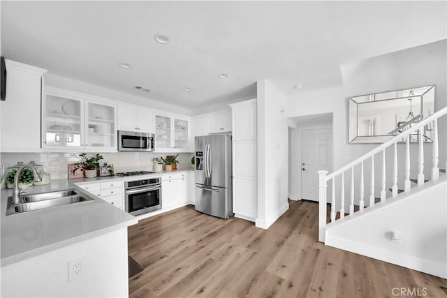 kitchen featuring white cabinetry, appliances with stainless steel finishes, sink, and light wood-type flooring