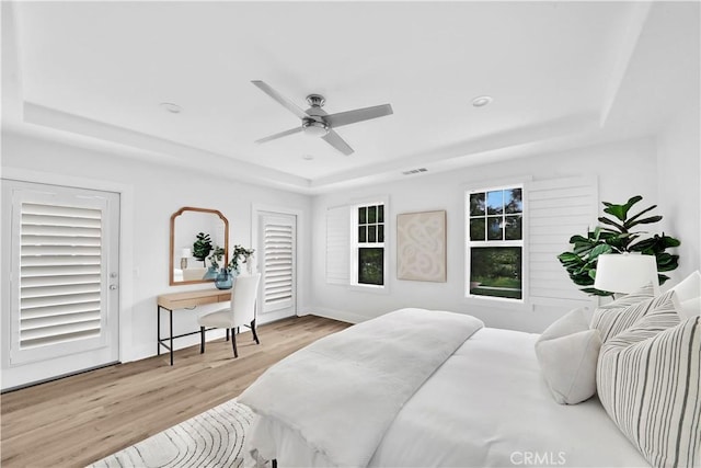 bedroom featuring ceiling fan, light wood-type flooring, and a raised ceiling