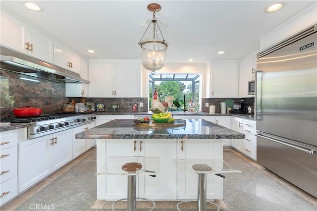 kitchen featuring white cabinetry, a breakfast bar area, built in appliances, and a kitchen island