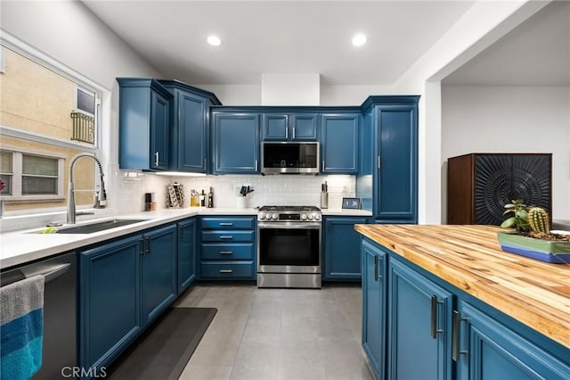 kitchen with blue cabinets, sink, backsplash, and appliances with stainless steel finishes