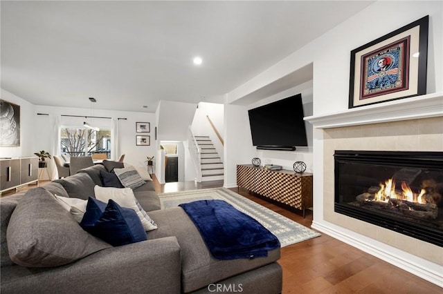 living room featuring a tiled fireplace and wood-type flooring