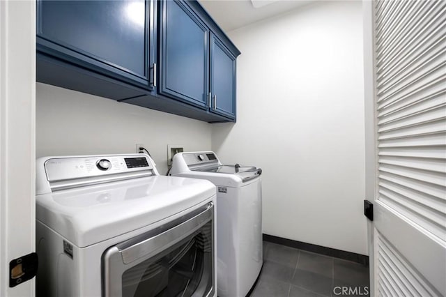 clothes washing area with cabinets, dark tile patterned floors, and washing machine and clothes dryer