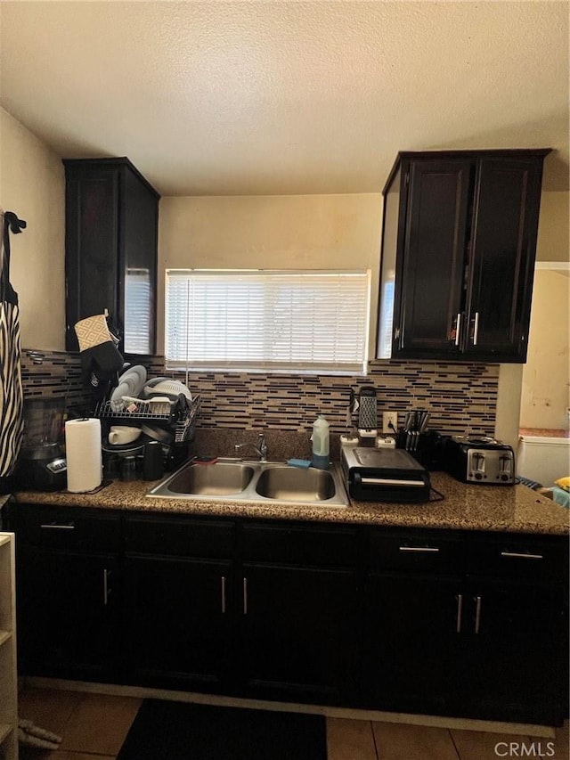 kitchen featuring tasteful backsplash, tile patterned floors, sink, and a textured ceiling