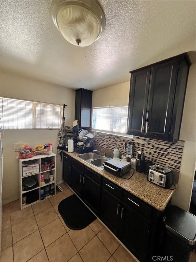 kitchen featuring light tile patterned flooring, sink, decorative backsplash, and a textured ceiling