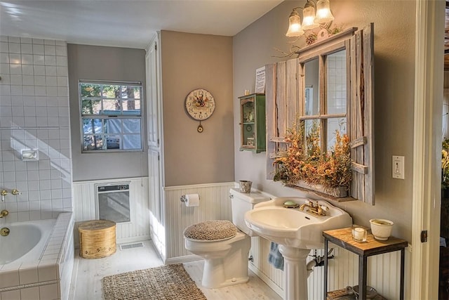 bathroom featuring toilet and tiled bath