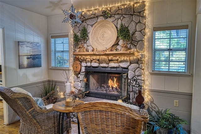 sitting room featuring wood-type flooring and a stone fireplace