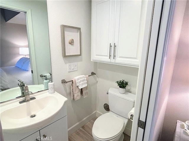 bathroom with wood-type flooring, vanity, and toilet