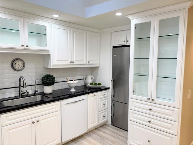 kitchen featuring sink, stainless steel fridge, dishwasher, white cabinetry, and backsplash