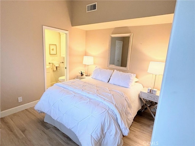 bedroom with hardwood / wood-style floors and ensuite bath