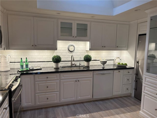 kitchen with stainless steel appliances, white cabinetry, sink, and light hardwood / wood-style flooring