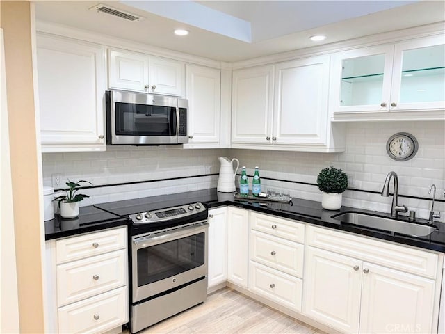 kitchen with white cabinetry, appliances with stainless steel finishes, sink, and backsplash