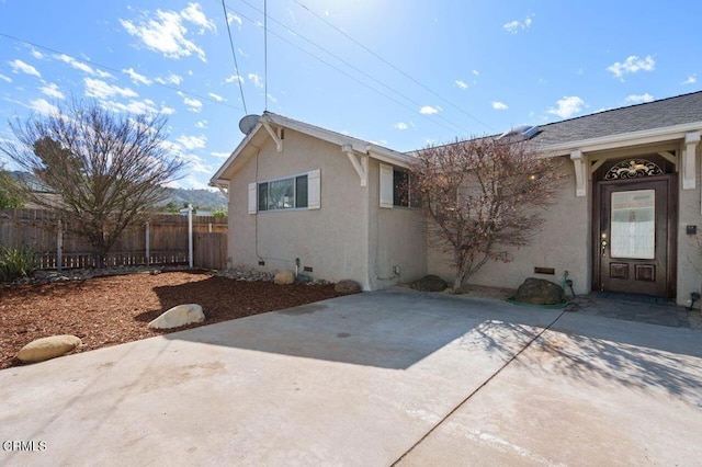 exterior space with fence, roof with shingles, crawl space, stucco siding, and a patio area