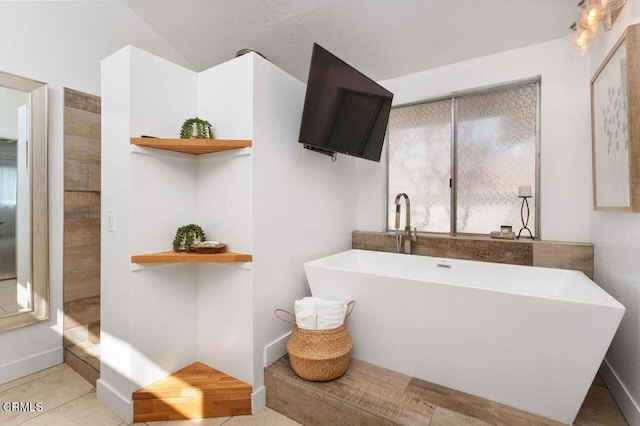 bathroom featuring a soaking tub and baseboards