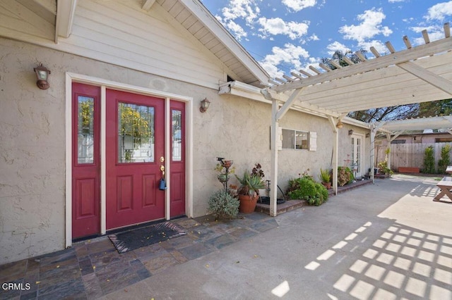 entrance to property with a patio area, fence, a pergola, and stucco siding