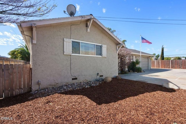 exterior space with an attached garage, fence, concrete driveway, crawl space, and stucco siding