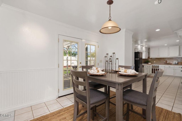 dining space with light tile patterned floors, ornamental molding, french doors, and wainscoting