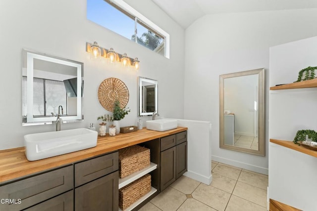 full bath featuring double vanity, high vaulted ceiling, tile patterned flooring, and a sink