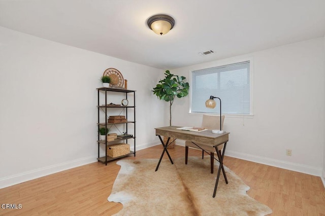 office featuring light wood-style flooring, visible vents, and baseboards