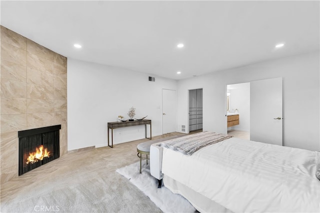 carpeted bedroom with ensuite bath and a fireplace