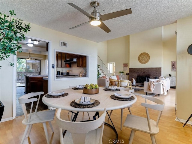 1923 Molino Ave Unit 303, Signal Hill, CA 90755 - dining space with stairway, ceiling fan, light wood finished floors, a textured ceiling, and a brick fireplace