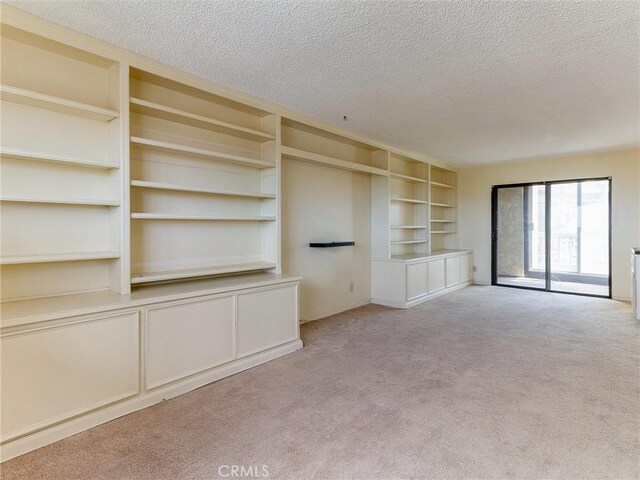 1923 Molino Ave Unit 303, Signal Hill, CA 90755 - unfurnished living room featuring carpet flooring, a textured ceiling, and built in shelves