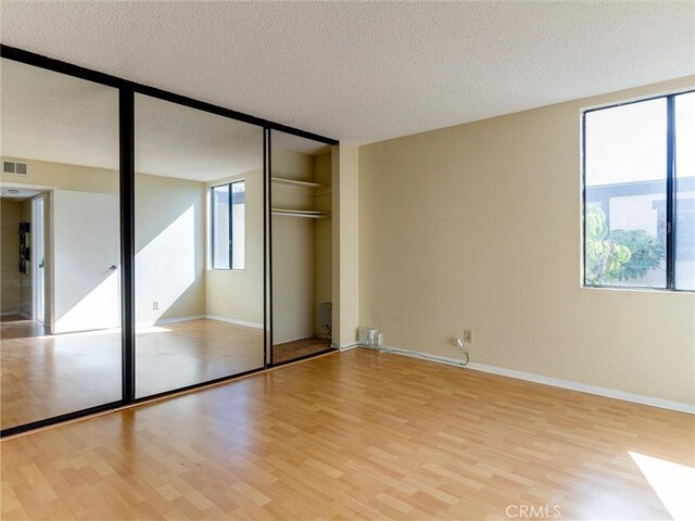 1923 Molino Ave Unit 303, Signal Hill, CA 90755 - unfurnished bedroom with light wood-style flooring, a textured ceiling, a closet, and baseboards