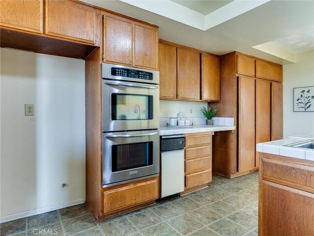 1923 Molino Ave Unit 303, Signal Hill, CA 90755 - kitchen featuring double oven, tile counters, brown cabinetry, and baseboards