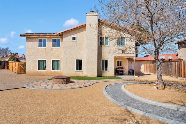 rear view of property with a patio and a fire pit