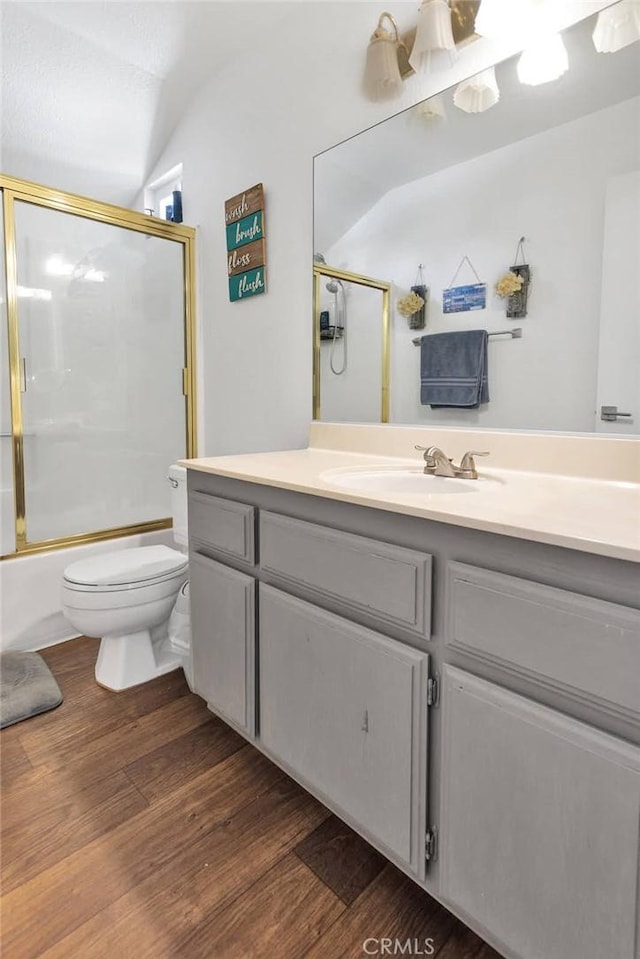 full bathroom featuring hardwood / wood-style flooring, enclosed tub / shower combo, vanity, and toilet