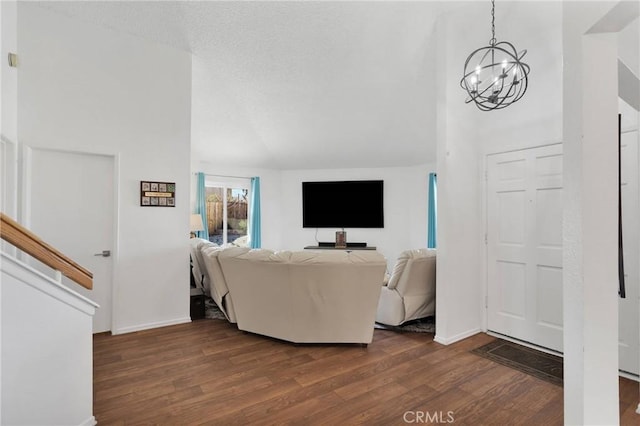 living room with dark wood-type flooring, lofted ceiling, a chandelier, and a textured ceiling