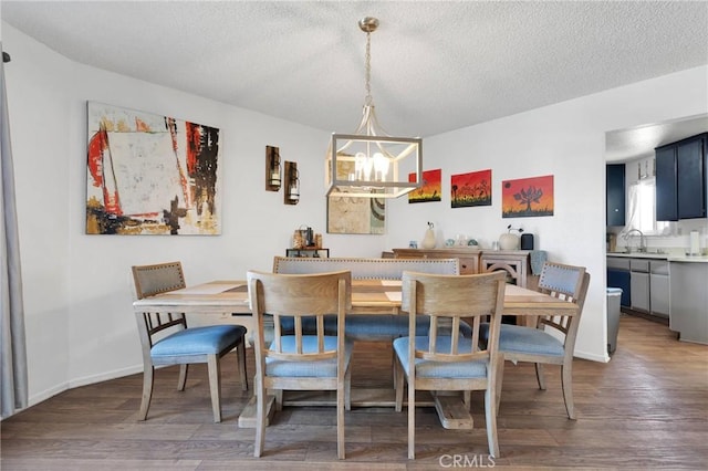 dining space with an inviting chandelier, sink, dark hardwood / wood-style floors, and a textured ceiling