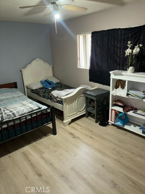 bedroom with ceiling fan, a textured ceiling, and light wood-type flooring