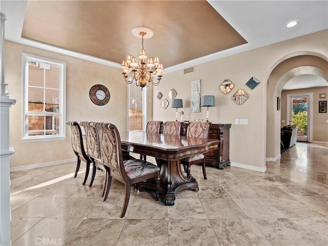 dining space featuring an inviting chandelier and a raised ceiling