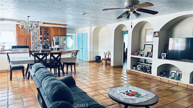 living area featuring built in features, light tile patterned flooring, a textured ceiling, and a ceiling fan