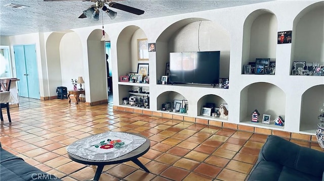 tiled living room featuring ceiling fan, built in shelves, visible vents, and a textured ceiling