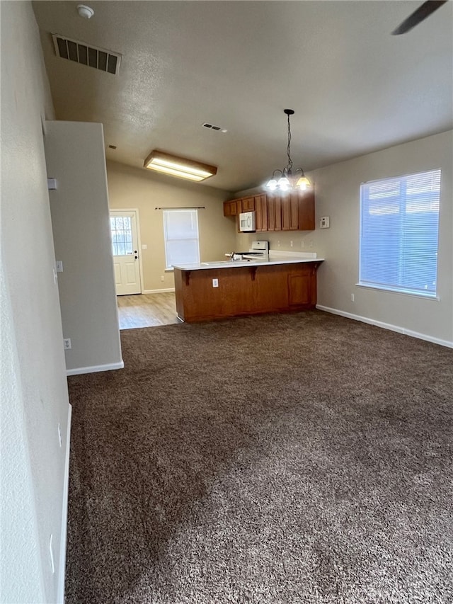 kitchen featuring range, hanging light fixtures, dark colored carpet, vaulted ceiling, and kitchen peninsula