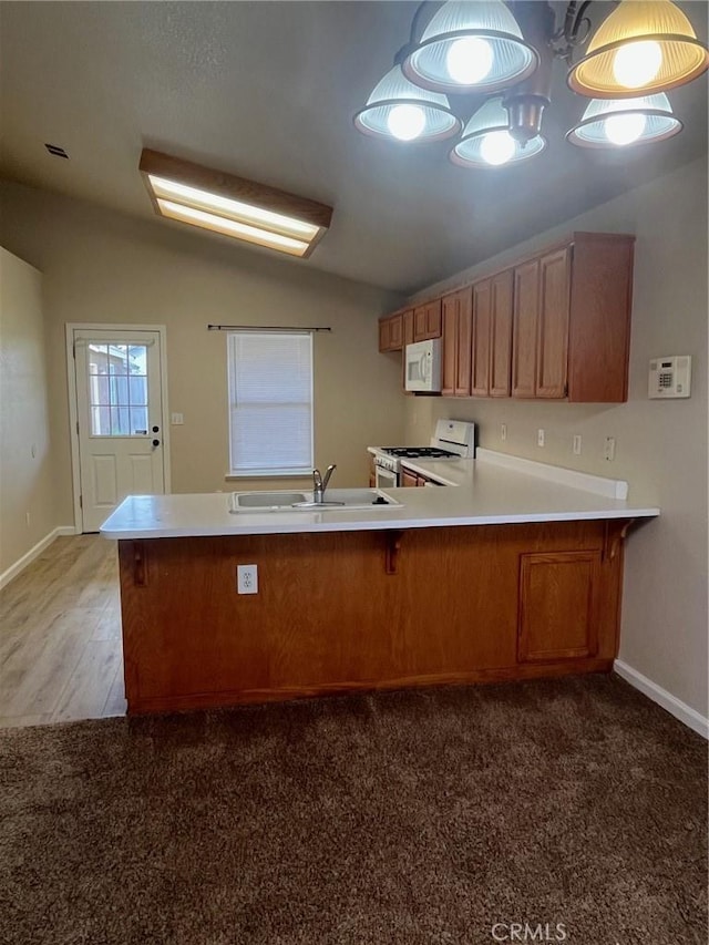 kitchen with sink, white appliances, dark carpet, vaulted ceiling, and kitchen peninsula