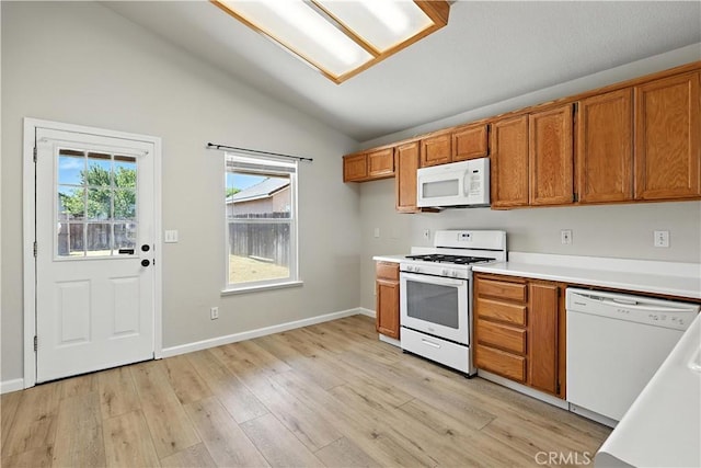 713 Vista Del Rey Dr, Atwater, CA 95301 - kitchen with vaulted ceiling, brown cabinets, white appliances, light countertops, and light wood-type flooring