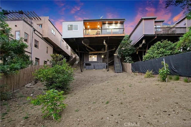 rear view of house with fence and a balcony