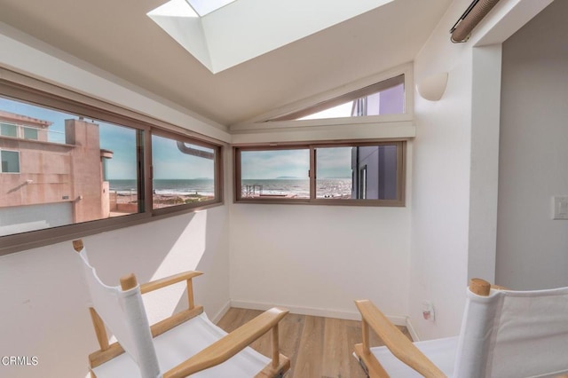 stairway with vaulted ceiling with skylight, wood finished floors, and baseboards