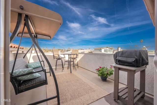 view of patio / terrace featuring a water view, a grill, and a balcony