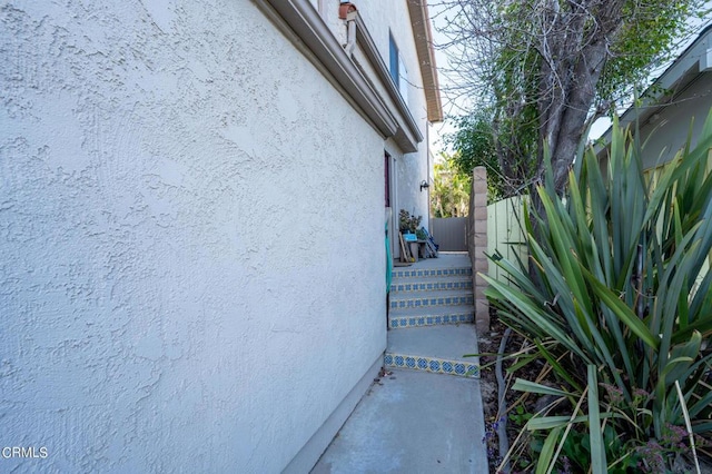 view of side of property with fence and stucco siding