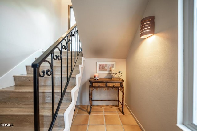 stairs with vaulted ceiling, baseboards, and tile patterned floors